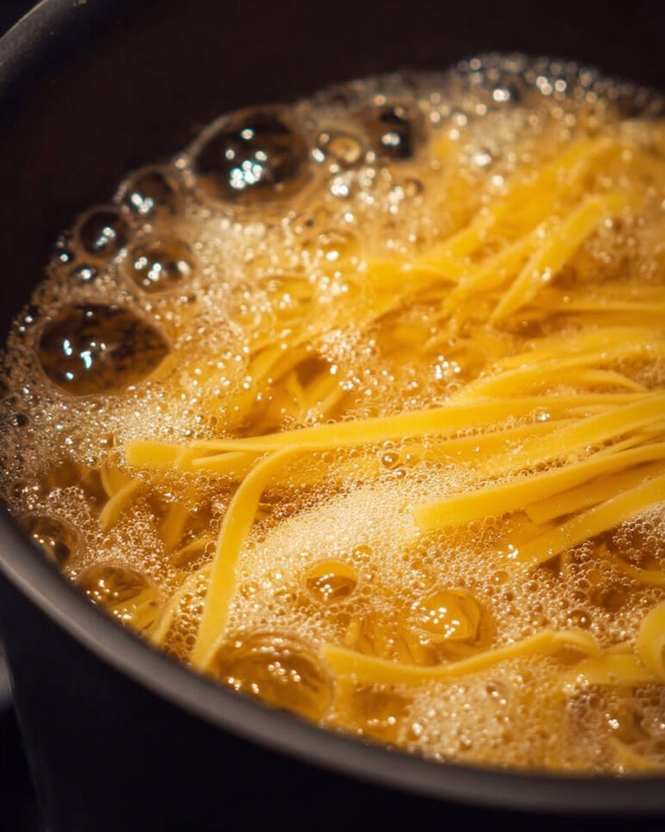 A close-up view of yellow pasta noodles boiling in a black pot filled with lively, bubbling water. The noodles have a smooth texture and are partially submerged in the frothy, clear liquid, with bubbles of different sizes visibly bursting on the surface. The pot's dark edge contrasts with the light color of the pasta and the golden bubbles of the boiling water. Photo taken with an iphone --ar 4:5 --v 7