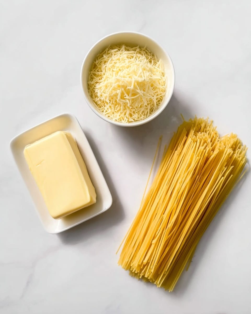 The image shows three items on a white marbled surface: a small pile of uncooked yellow spaghetti on the right side, a small white bowl filled with grated pale yellow cheese above the spaghetti, and a rectangular white plate with a single stick of light yellow butter on the left side. All items are neatly arranged with clear separation between them, and the lighting is bright, highlighting the textures and colors clearly. Photo taken with an iphone --ar 4:5 --v 7