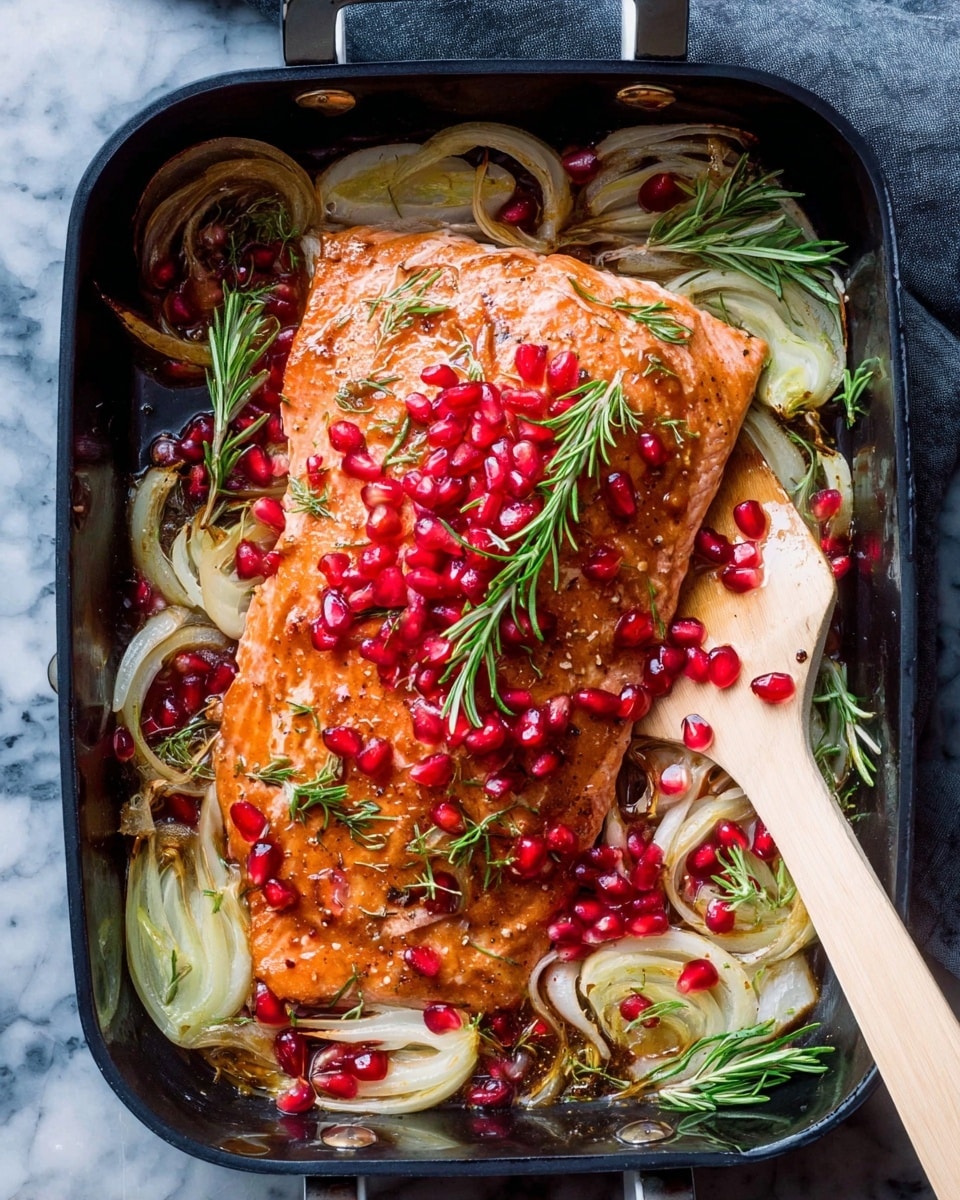In a black roasting pan, there is one large piece of cooked salmon with a light brown glaze on the top. The salmon is covered with bright red pomegranate seeds scattered all over, and green sprigs of rosemary placed on and around it. Underneath the salmon, there is a layer of thinly sliced white and pale green fennel bulbs and shallots with a slightly cooked look. The pan is placed on a white marbled surface. A light-colored spatula is visible on the right side, touching the salmon. Photo taken with an iphone --ar 4:5 --v 7