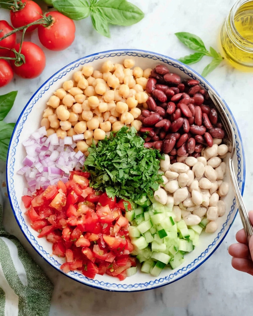 A white bowl with a blue rim holds seven distinct layers of fresh salad ingredients arranged in sections: pale yellow chickpeas at the top left, dark red kidney beans at the top right, light pink diced onions at the middle left, a central pile of bright green chopped cilantro, light tan white beans at the middle right, light green diced celery below the onions, and bright red diced tomatoes next to celery at the bottom left. Pieces of sliced cucumber with dark green skin and pale green inside form a curved section next to the tomatoes and celery on the bottom right. The bowl sits on a white marbled surface with tomatoes and basil leaves in the top left of the frame and a jar of light yellow dressing visible at the bottom left. A woman's hand holding a silver fork is partially visible near the bottom. Photo taken with an iphone --ar 4:5 --v 7