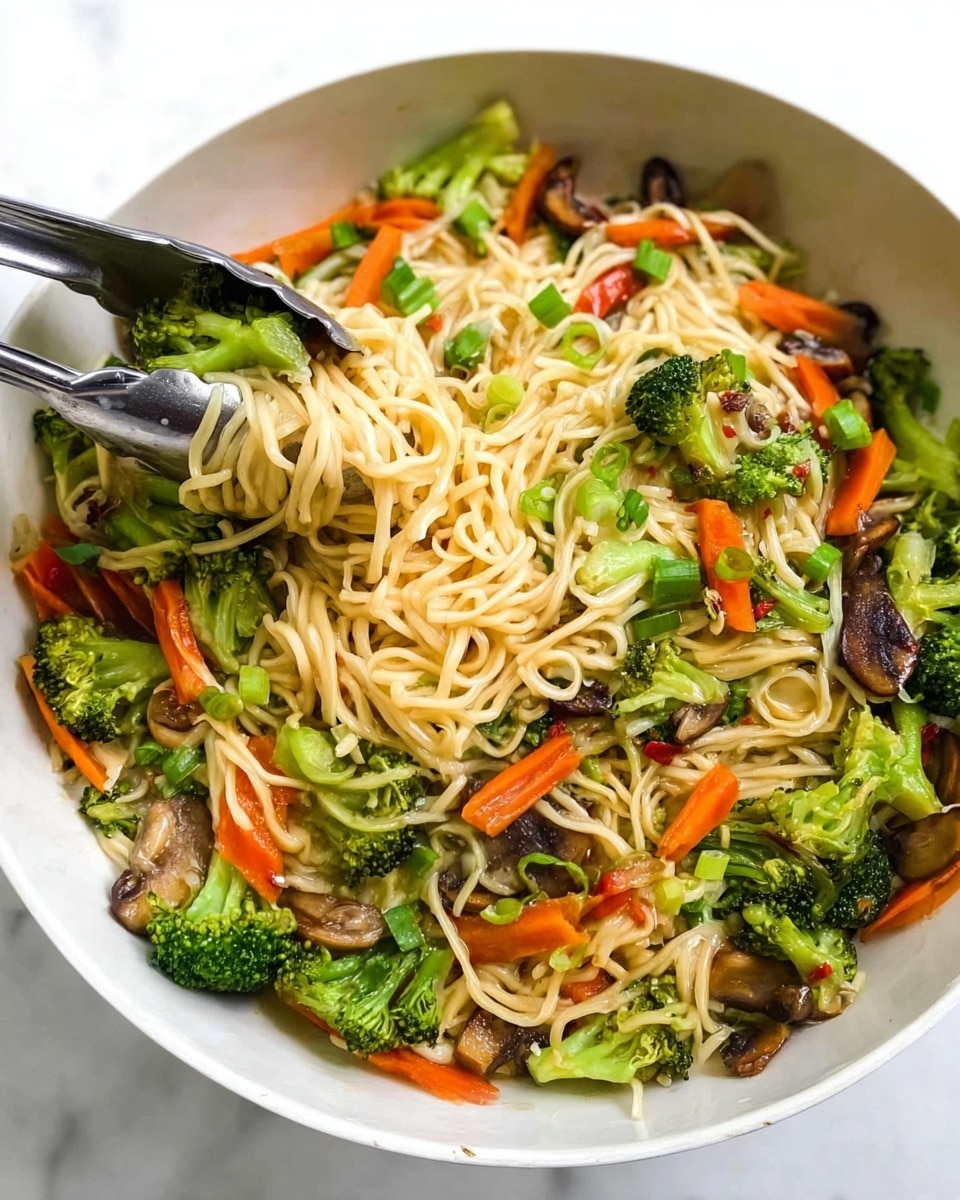 A white bowl filled with a mix of noodles and vegetables sits on a white marbled surface. The noodles are light yellow and tangled in the center, surrounded by bright green broccoli pieces and orange carrot slices scattered evenly. There are some small bits of green scallions and brown mushrooms mixed in, adding texture and color contrast. A silver tong is picking up some noodles and vegetables from the bowl. The whole scene is bright and fresh, showing the different shapes and colors clearly. photo taken with an iphone --ar 4:5 --v 7