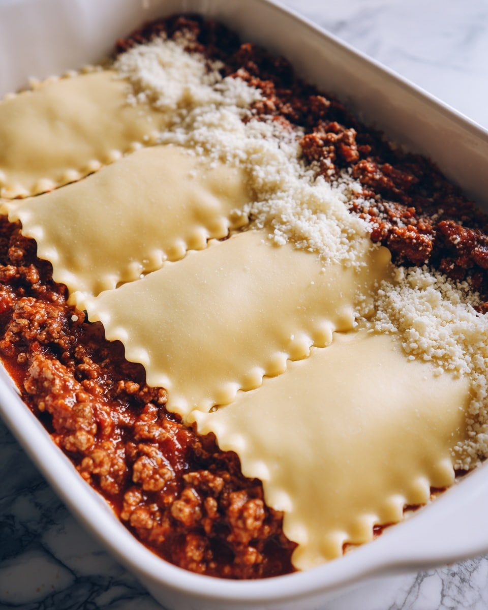 The image shows a close-up of a lasagna layer being made in a white dish. On the right side, there is a meat and tomato sauce mixed with a sprinkling of white grated cheese. Next to this sauce are three wide, smooth, pale yellow pasta sheets, each with ruffled edges, layered flat and overlapping slightly from left to right, covering part of the sauce. The surface beneath shows a white marbled texture. Photo taken with an iphone --ar 4:5 --v 7
