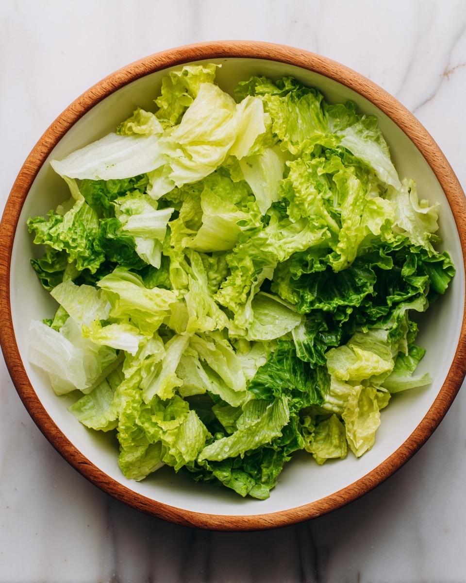 A white bowl with a wooden rim filled with shredded fresh lettuce leaves in different shades of green, some lighter and some darker. The leaves have a crisp texture and look juicy. The bowl is set on a white marbled surface. photo taken with an iphone --ar 4:5 --v 7