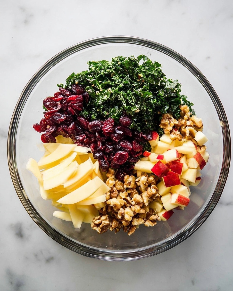 A clear glass bowl sits on a white marbled surface, filled with four distinct layers of ingredients. The bottom left section shows thin, pale yellow cheese slices with a smooth, slightly curled texture. Directly above them is a pile of deep red dried cranberries, small and slightly wrinkled. To the right of the cranberries is a mound of finely chopped dark green kale with a leafy texture. The top right section is covered with chopped light brown walnuts, rough and uneven in shape. The bottom right corner has small chunks of red and yellow apple with skin on, showing a crisp and fresh texture. photo taken with an iphone --ar 4:5 --v 7