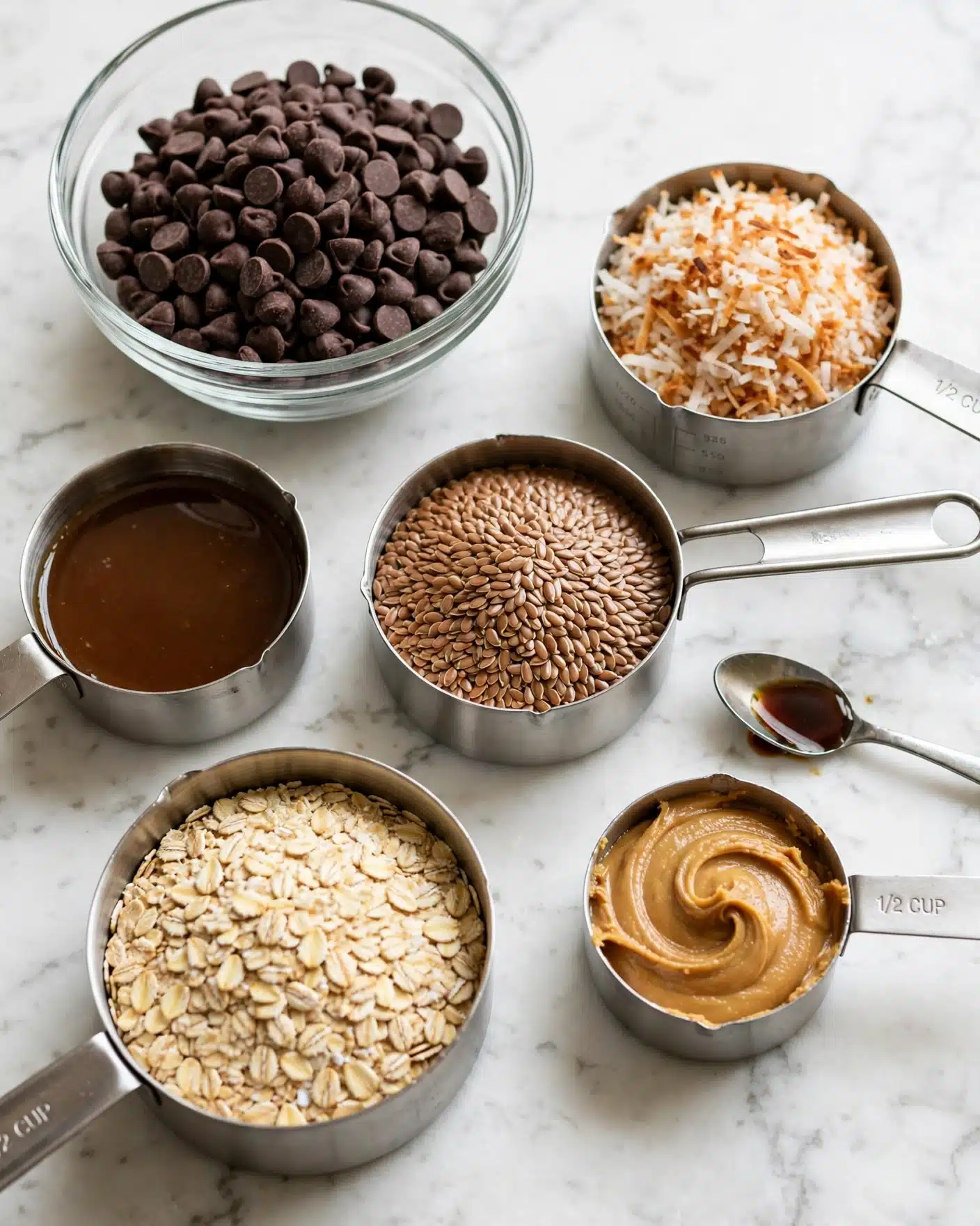 The image shows six measuring cups and a clear glass bowl arranged on a white marbled surface. The clear glass bowl at the top left is filled with dark brown chocolate chips. At the top right, a measuring cup holds toasted shredded coconut, which is light brown and white in color. Below the chocolate chips, a measuring cup contains a brown syrup-like liquid. In the center, a measuring cup is filled with light brown flaxseeds, with a coarse texture. Below the flaxseeds, a larger measuring cup holds pale yellow rolled oats, flat and dry. To the right of the oats, a 1/2 cup measuring cup contains smooth, light brown peanut butter that is swirled. Above the peanut butter, a small teaspoon holds a dark brown liquid, likely vanilla extract. The bowls and cups are arranged with space between them, casting faint shadows. Photo taken with an iphone --ar 4:5 --v 7